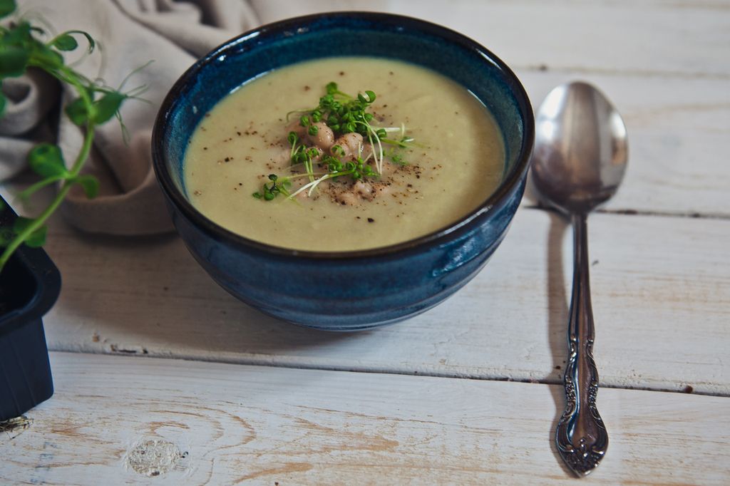 slika recepta - porova juha, servirana v lepi keramični skodelici, posuta z začimbami in mikrozelenjem, zraven je žlica