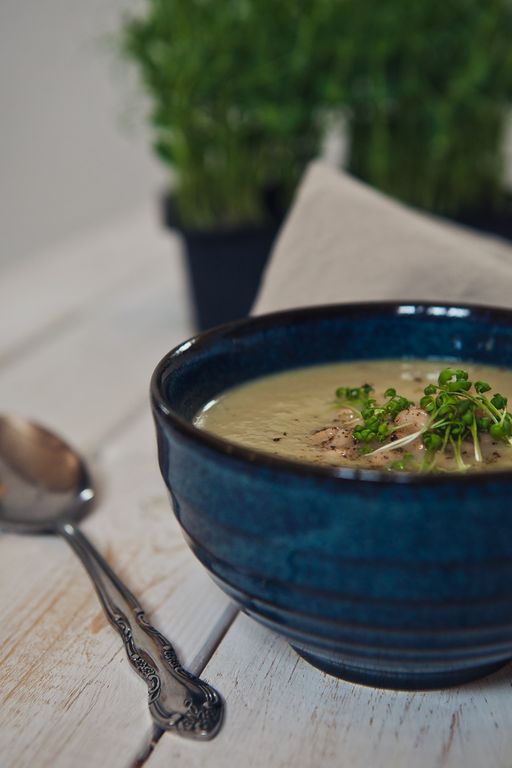 slika recepta - porova juha, servirana v lepi keramični skodelici, posuta z začimbami in mikrozelenjem, zraven je žlica