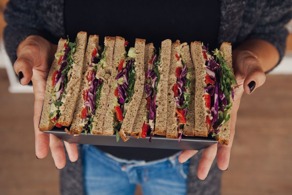 zelenjavni toast sendviči na pladnju v ženskih rokah