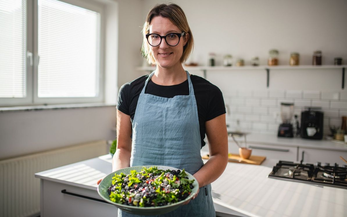 Aleksandra v kuhinji drži v roki mešano zelenjavno skledo